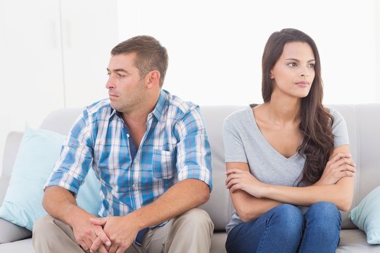 Couple looking away while sitting on sofa