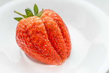 Fresh strawberry on white dish.