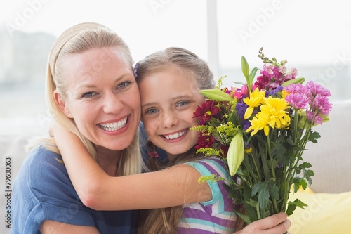Mother with bouquet embracing daughter in house