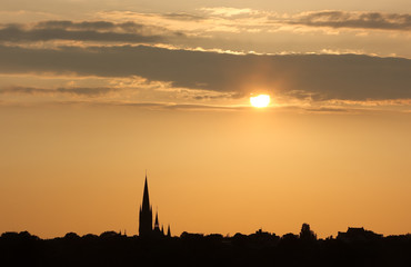 Evening city. Sunset in the golden tones above contour of the city. The picture shows the contour of the church of St. Johannes in Hamburg.