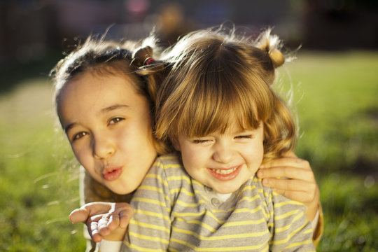 Ni&ntilde;a soplando beso mientras abraza a su amiguita