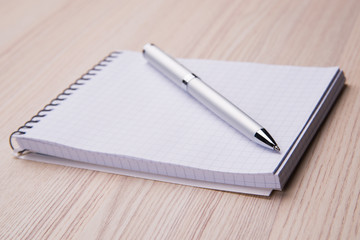 Blank notepad with pen on office wooden table