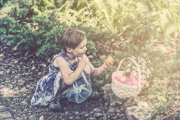 Girl Looks at an Easter Egg from her Basket - Retro Filtered