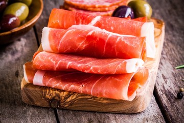 thin slices of prosciutto with olives on a cutting board