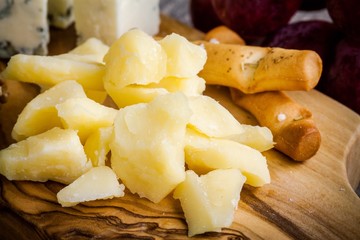Parmesan cheese close-up with bread sticks on a wooden board