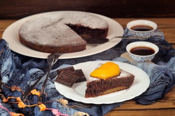 Chocolate cake with mango and black tea on blue cloth