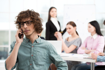 Young businessman using phone in office