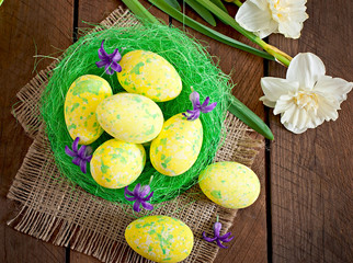 Easter eggs and flowers on wooden background
