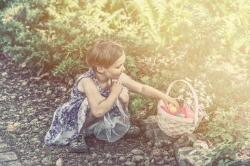 Naklejka premium Girl Collects Colorful Easter Eggs in a Basket - Retro Filtered