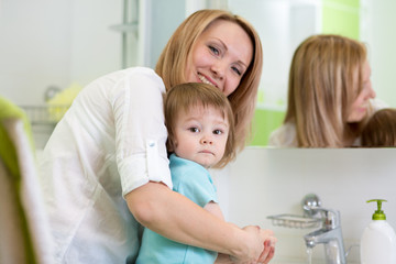 mother teaches kid washing hands in bathroom