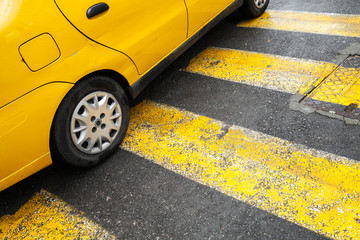Yellow taxi car stands on pedestrian crossing