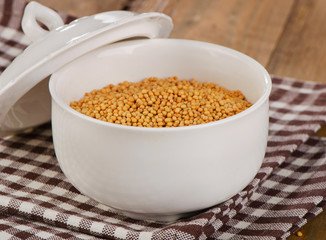 Mustard seeds in a white bowl.