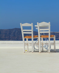 Two empty white chairs against mountains and sky