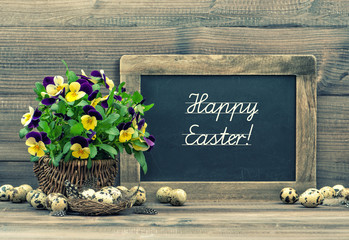 Easter decoration eggs, pansy flowers and vintage blackboard