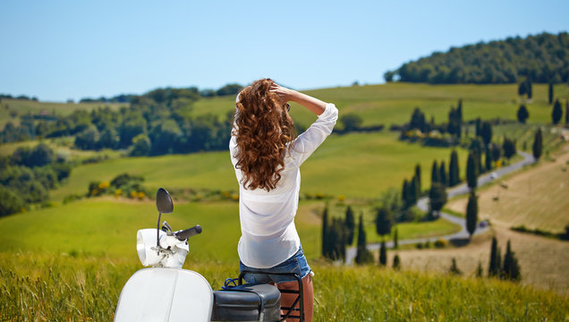 Young beautiful italian woman sitting on a italian scooter in tu