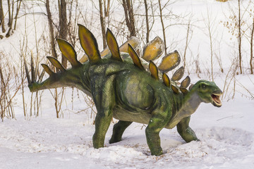 plastic figure of a dinosaur in dinopark on snow background © alfaori