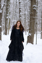 Woman in black dress in winter forest