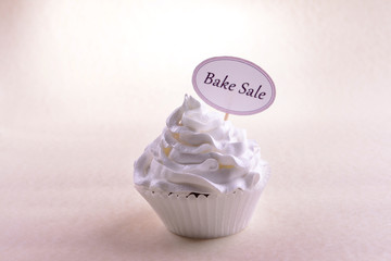 Delicious cupcake with inscription on table on beige background
