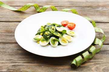 Salad with quail egg and basil in plate with measuring tape