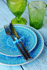 Empty colorful plate, glasses and silverware set on wooden