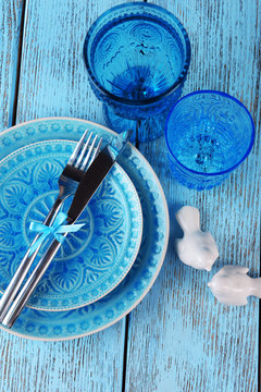 Empty colorful plate, glasses and silverware set on wooden