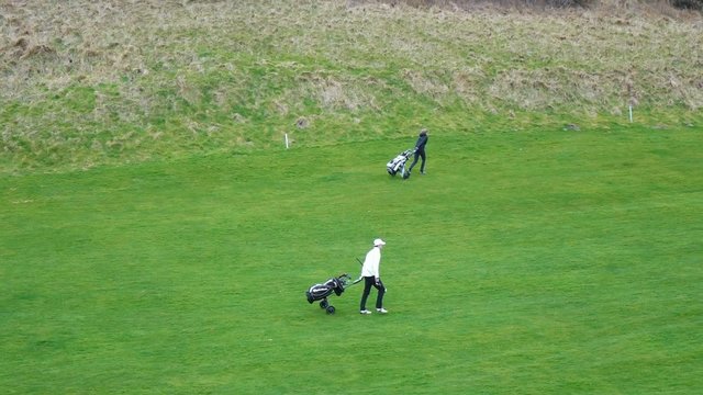 Deux golfeurs marchant sur un green