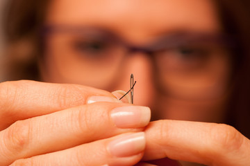 Woman putting string through needle