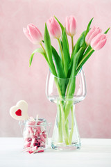 Beautiful pink tulips in vase with jar of paper