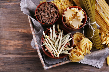 Different types of pasta in wicker basket with fabric
