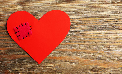 Obraz premium Patch on broken heart on wooden background