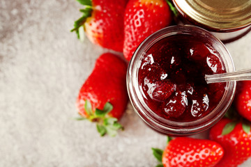 Jars of strawberry jam with berries on tray close up