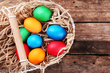 Easter eggs in basket on vintage wooden planks background