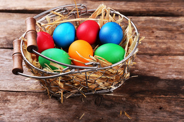 Easter eggs in basket on vintage wooden planks background