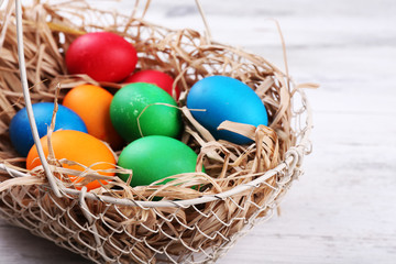 Easter eggs in basket on vintage wooden planks background