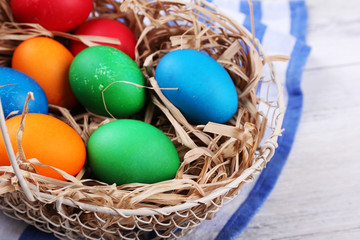 Easter eggs in basket on vintage wooden planks background
