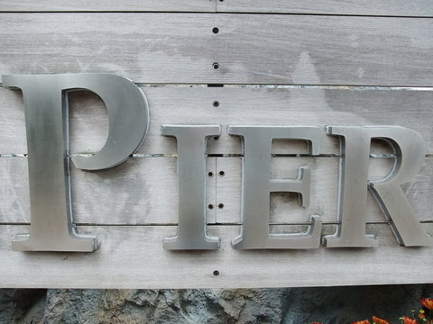 A metal Pier sign panel  on timber board