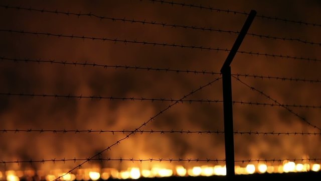 Night fire in a field view through Barbed wire