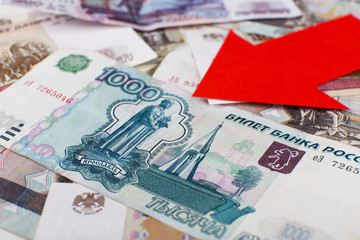 Red arrow on Russian money as depreciation of currency, closeup