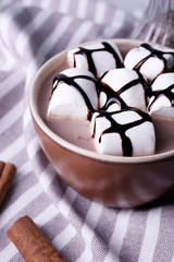 Cup of cocoa with marshmallows on stripped napkin, closeup