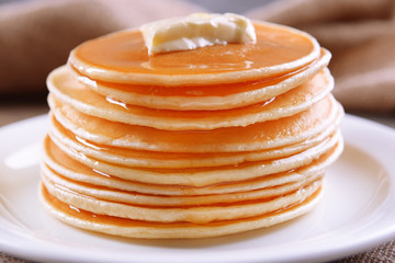 Delicious pancakes with honey on plate on table close-up