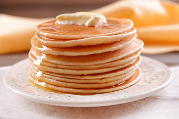 Delicious pancakes with honey on plate on table close-up