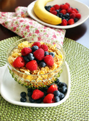 A bowl of breakfast cereal topped with blueberries and raspberri