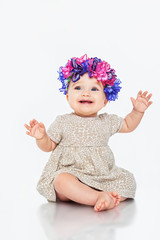 Beautiful little girl wearing a wreath, on a gray background