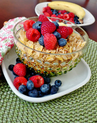 A bowl of breakfast cereal topped with blueberries and raspberri