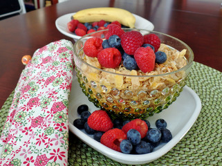 A bowl of breakfast cereal topped with blueberries and raspberri