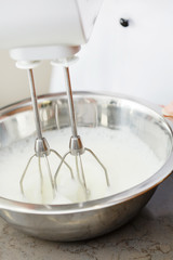 Fototapeta na wymiar Mixing white egg cream in bowl with motor mixer