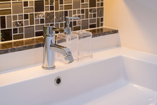 washbasin with faucet and liquid soap bottle at home