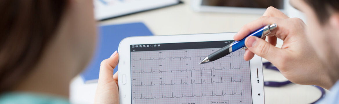 Modern cardiologists analyzing electrocardiogram