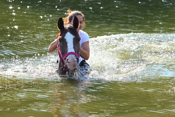 Girl swiming with her horse in river