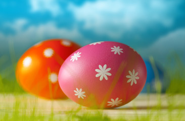 Colored Easter eggs on the grass and blue sky background